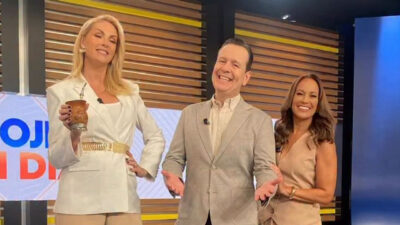Ana Hickmann de blazer branco com cuia de mate, Celso Zucatelli ao centro de terno cinza e Renata Alves de vestido bege sorrindo no estúdio da Record