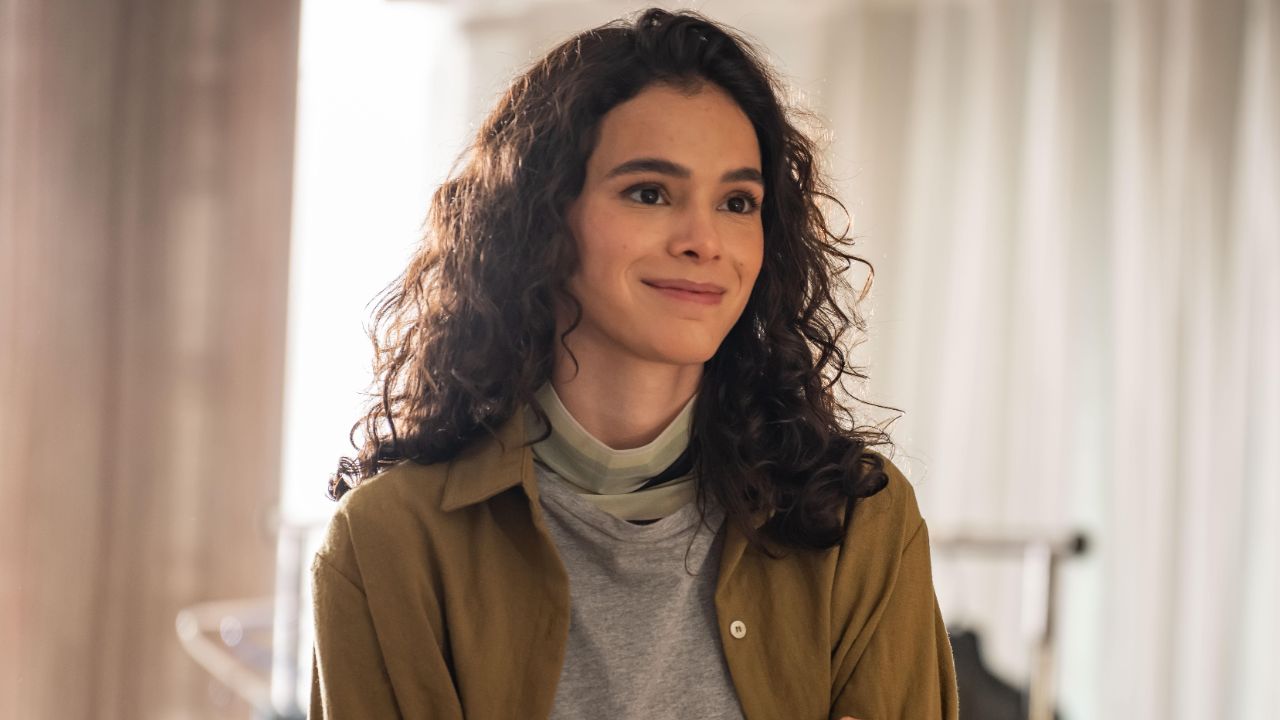 Bruna Marquezine como Bia na série Amor da Minha Vida, sorrindo levemente com cabelos cacheados soltos, vestindo jaqueta mostarda e blusa cinza