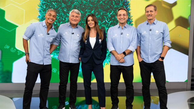 Dodô, Cléber Machado, Paloma Tocci, Maurício Noriega e Sálvio Spinola posam no estúdio da Record, homens vestem camisa azul e Paloma terno azul marinho