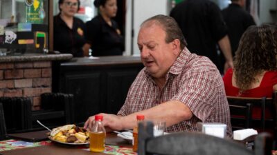 Erick Jacquin, de camisa xadrez, analisa um prato de comida nordestina em um restaurante popular, durante as gravações do reality Pesadelo na Cozinha