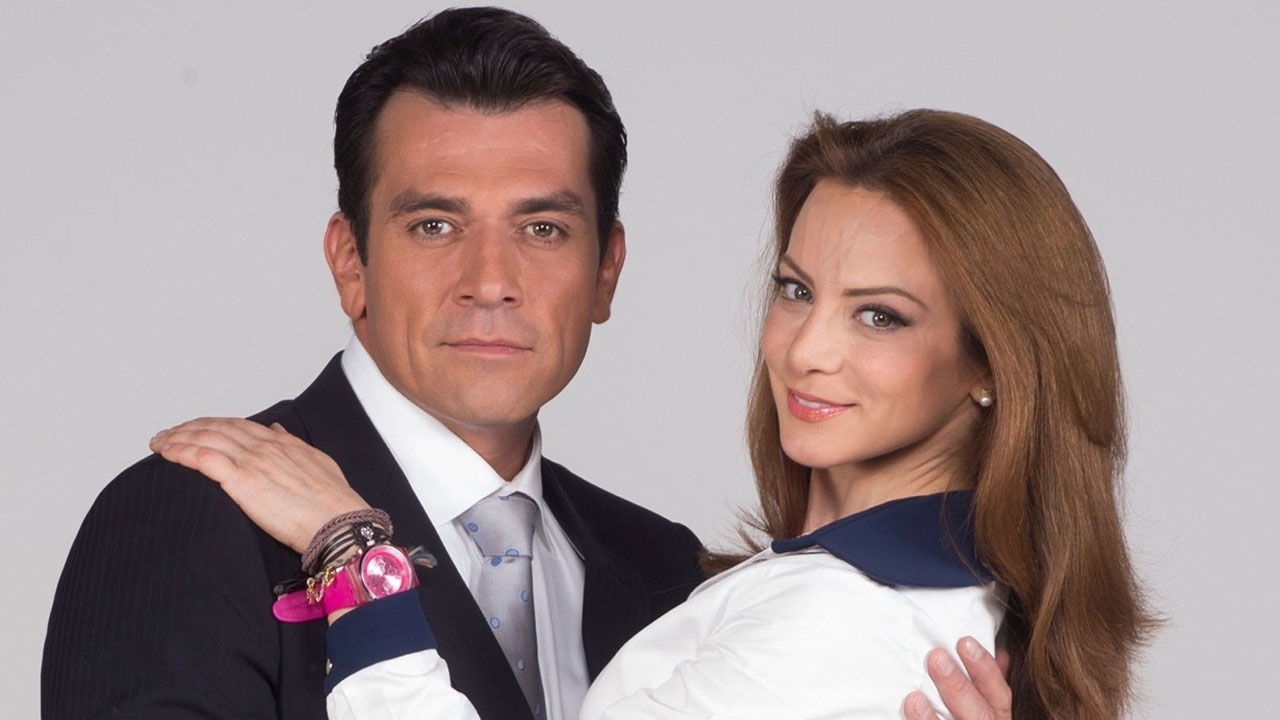 Fernando (Jorge Salinas) encara a câmera enquanto Ana Leal (Silvia Navarro) sorri de lado e apoia a mão no ombro dele, em foto de divulgação da novela Meu Coração é Teu