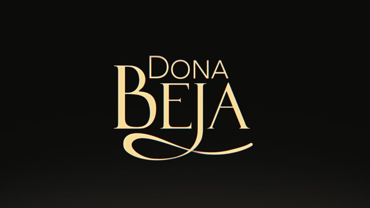 Logotipo da novela Dona Beja escrito em letras douradas e elegantes, com destaque para a letra B alongada, centralizado sobre um fundo preto fosco
