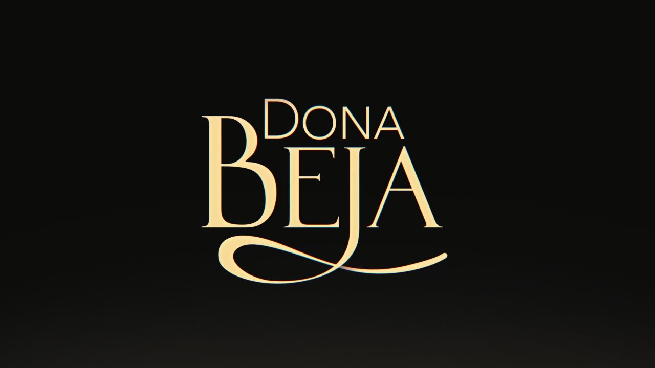 Logotipo da novela Dona Beja escrito em letras douradas e elegantes, com destaque para a letra B alongada, centralizado sobre um fundo preto fosco