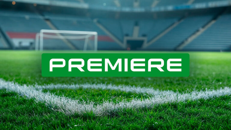 Logotipo do canal Premiere em letras brancas sobre retângulo verde centralizado em campo de futebol com gramado em destaque e trave ao fundo desfocada