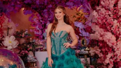 Lorena Queiroz posa com vestido verde tomara que caia e saia volumosa em cenário decorado com flores rosas e roxas em festa temática