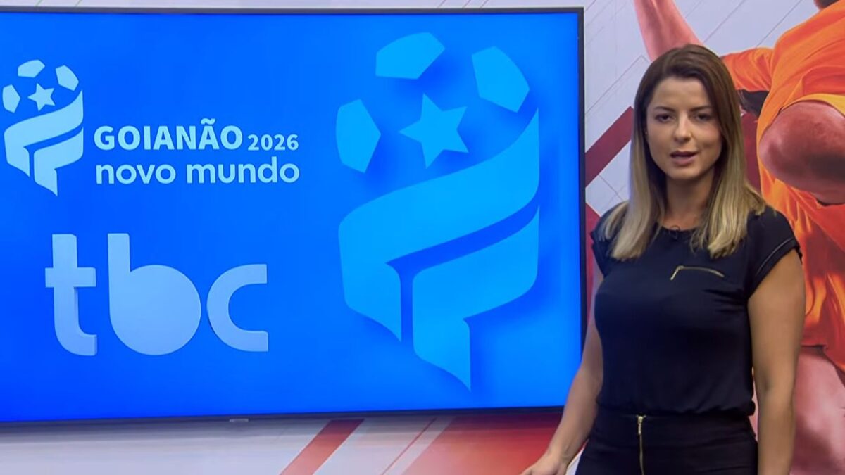 Apresentadora Thaís Freitas vestindo blusa preta em estúdio da TBC diante de telão azul com logotipos do Goianão 2026 Novo Mundo TBC