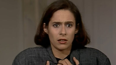 Ingrid Figueroa interpretada por Andréa Beltrão com expressão assustada segura a roupa em cena da novela Rainha da Sucata