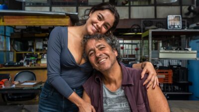 Sophie Charlotte abraça Marcos Palmeira sorrindo em cenário de oficina nos bastidores da novela Três Graças