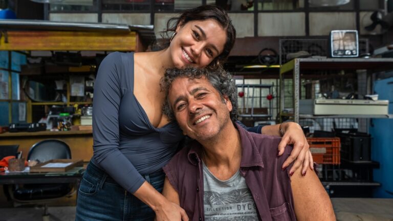 Sophie Charlotte abraça Marcos Palmeira sorrindo em cenário de oficina nos bastidores da novela Três Graças