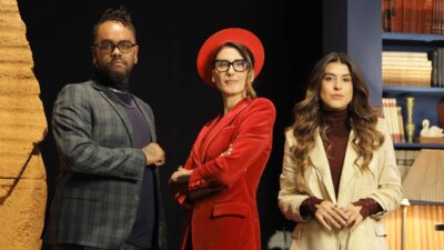 Fabão, Paola Carosella e Luana Zucoloto posam no estúdio do Infiltrado na Cozinha com estante ao fundo