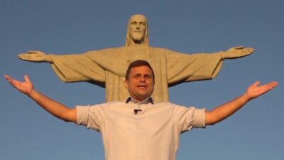 Fábio Barretto abre os braços em frente ao Cristo Redentor no Rio de Janeiro imitando a posição da estátua ao fundo