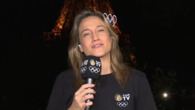 Fernanda Gentil segura microfone da CazéTV com Torre Eiffel iluminada ao fundo durante cobertura das Olimpíadas de Paris