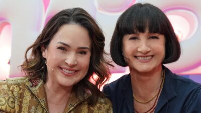 Gabriela Duarte e Zezé Polessa sorrindo lado a lado no palco do Caldeirão com Mion em estúdio iluminado