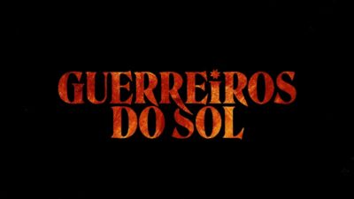 Logotipo da novela Guerreiros do Sol em letras grandes com textura alaranjada sobre fundo preto