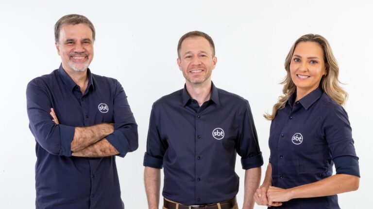 Mauro Beting, Tiago Leifert e Nadine Bastos posam sorrindo com camisas azul-marinho com logo do SBT em foto promocional de transmissão esportiva
