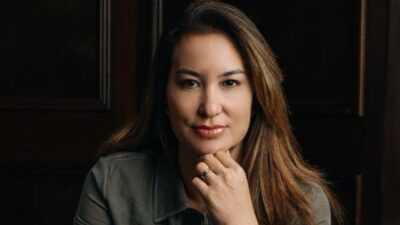 Nathalie Pilan posa com mão apoiada no queixo em retrato com fundo escuro e iluminação suave destacando o rosto