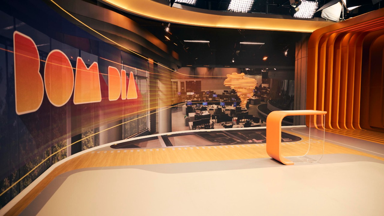 Estúdio do Bom Dia Brasil vazio com telão exibindo nome do telejornal bancada moderna e redação ao fundo