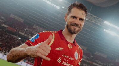 Paulo Ricardo sorri e faz gesto positivo com a mão em campo de futebol usando uniforme vermelho diante da torcida no estádio