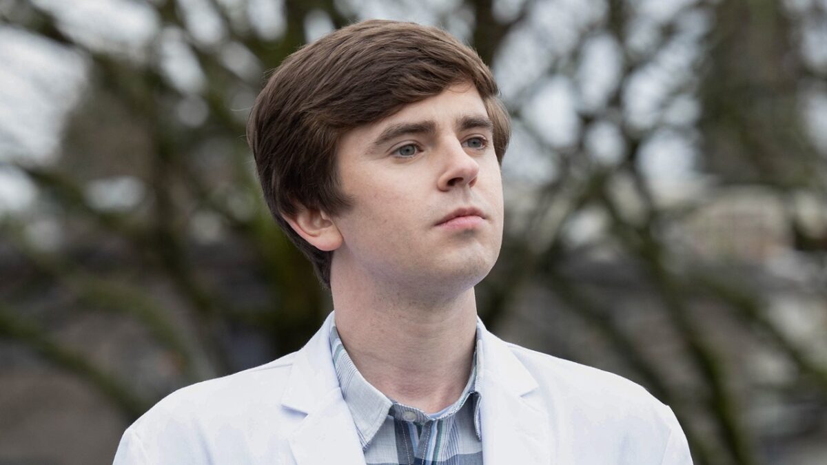 Shaun Murphy (Freddie Highmore) observa à distância com expressão séria em ambiente externo em cena de The Good Doctor