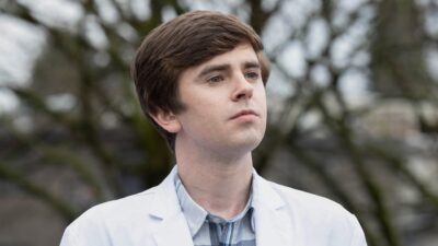Shaun Murphy (Freddie Highmore) observa à distância com expressão séria em ambiente externo em cena de The Good Doctor
