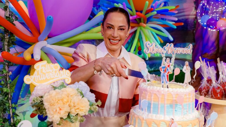 Silvia Abravanel corta bolo decorado com personagens e balões coloridos em festa do programa Sábado Animado com tema infantil