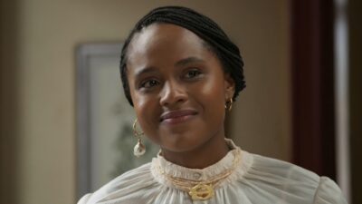 Duda Santos como Alika em cena da novela A Nobreza do Amor usando blusa clara e brincos dourados pendentes
