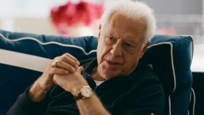 Antonio Fagundes como Arthur conversa sentado em sofá azul em cena da novela Quem Ama Cuida