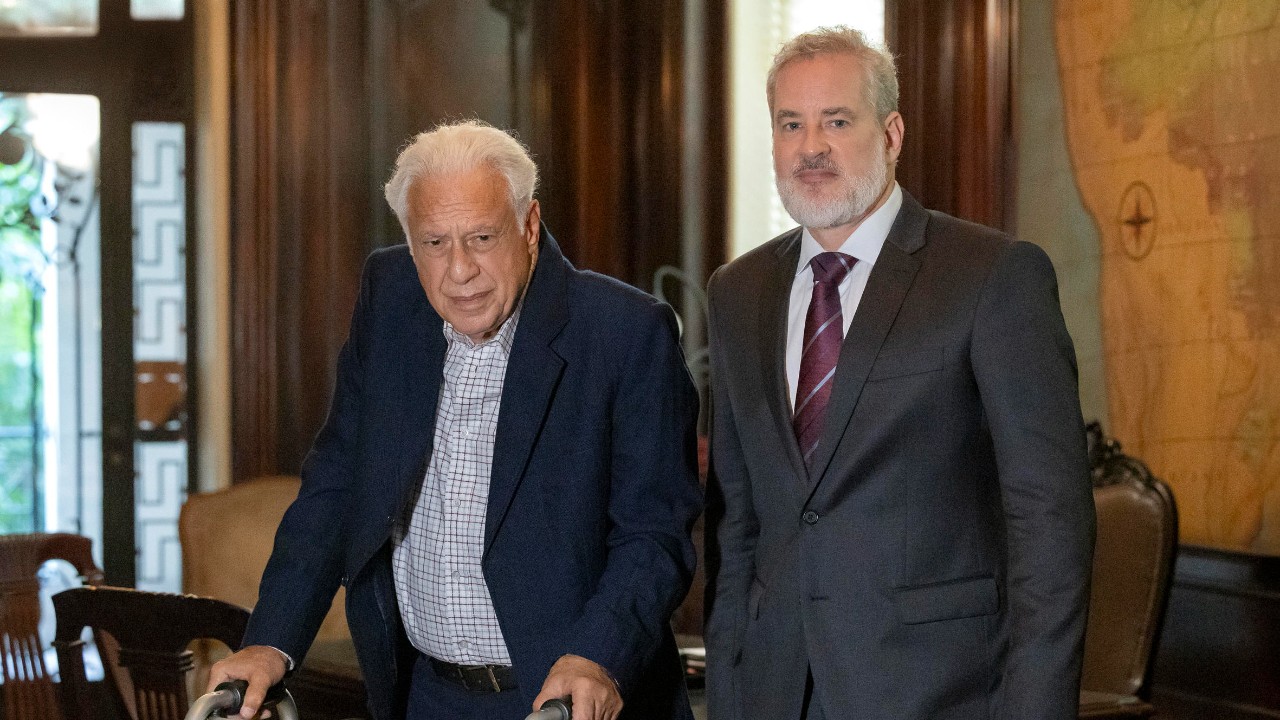 Arthur (Antonio Fagundes) usa andador ao lado de Ademir (Dan Stulbach) em escritório na novela Quem Ama Cuida