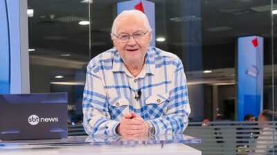 Boris Casoy apoia as mãos na bancada do SBT News em estúdio da emissora