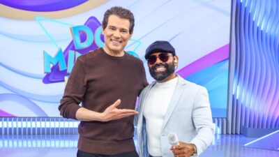 Celso Portiolli e cantor Pablo posam sorrindo no palco do Domingo Legal durante participação no programa