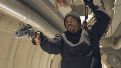 Ice Cube como Darius Stone aponta arma em corredor metálico em cena do filme Triplo X 2
