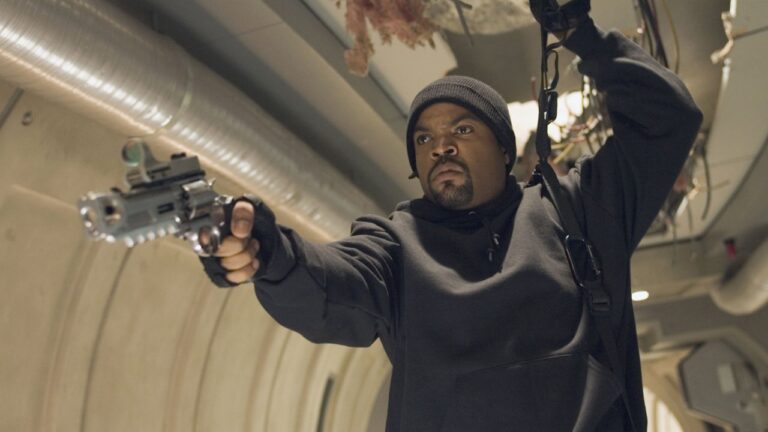 Ice Cube como Darius Stone aponta arma em corredor metálico em cena do filme Triplo X 2