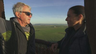 Feodor Nenov e Monica Teixeira conversam dentro de balão durante gravação do Globo Repórter sobre paisagem rural ao fundo