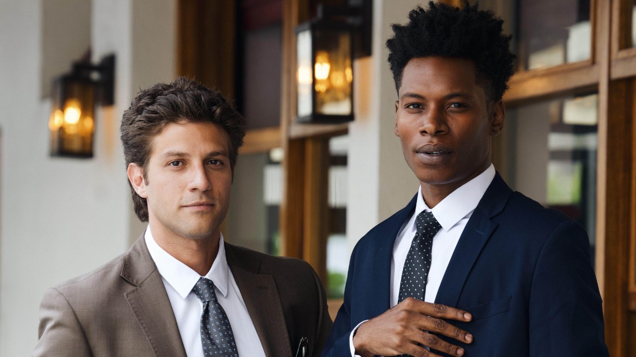 Pedro (Chay Suede) e Cleber (Breno Ferreira) aparecem de terno em cena da novela Quem Ama Cuida