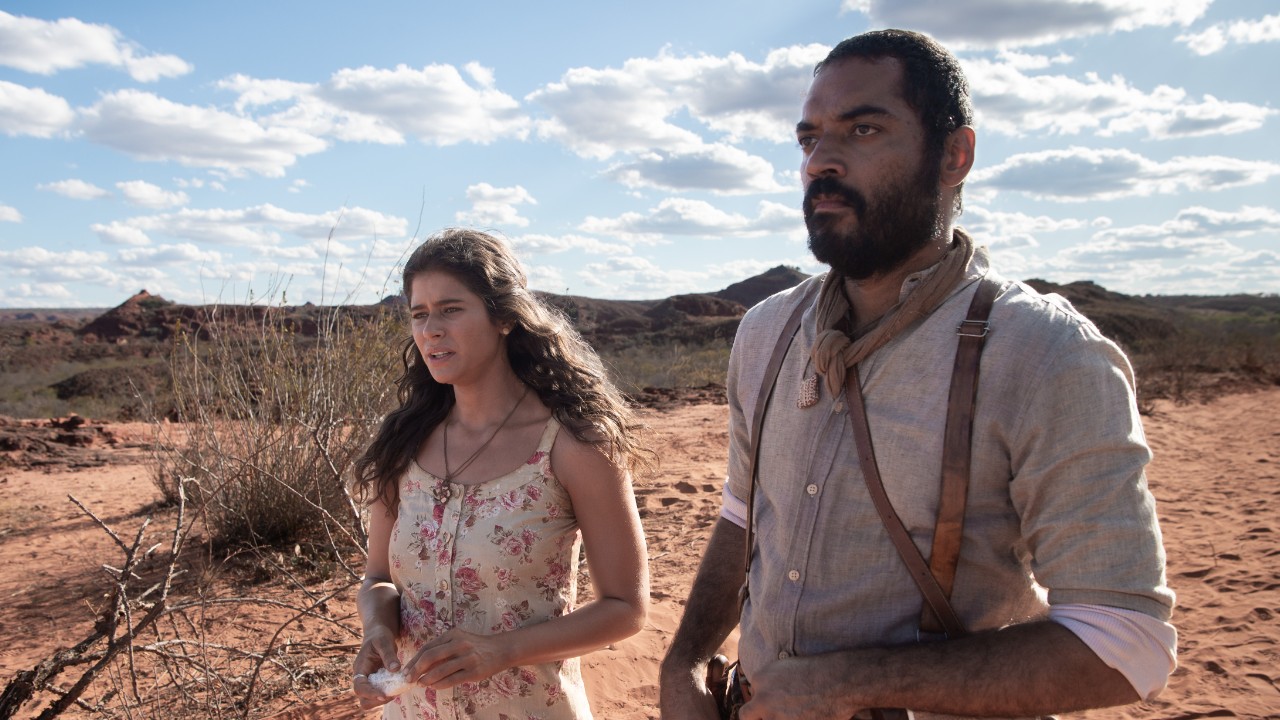 Rosa (Isadora Cruz) e Josué (Thomas Aquino) caminham pelo sertão em cena da novela Guerreiros do Sol