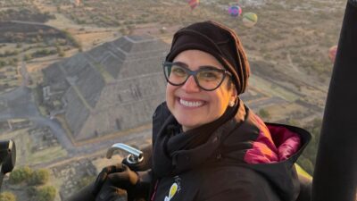 Sandra Annenberg sorri durante voo de balão sobre Teotihuacán com as Pirâmides do Sol e da Lua ao fundo no México