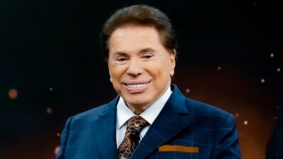 Silvio Santos sorri de terno azul durante gravação de programa no SBT