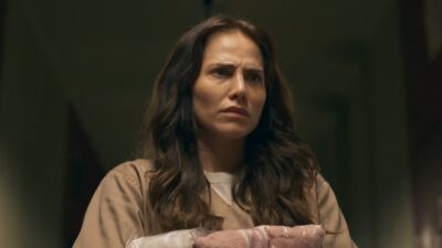 Adriana (Leticia Colin) com expressão tensa segurando roupas em penitenciária na novela Quem Ama Cuida