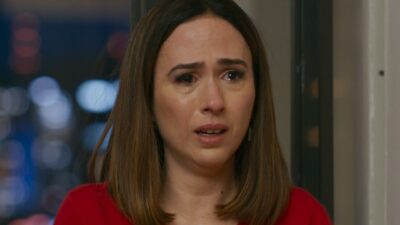 Brigitte (Tatá Werneck) com lágrimas nos olhos e expressão aflita em cena da novela Quem Ama Cuida diante de janela iluminada à noite