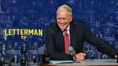 David Letterman sorrindo atrás da mesa com microfone em imagem promocional do canal Letterman TV