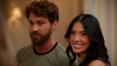 André Luiz Frambach com barba e camiseta verde ao lado de Ana Castela de cabelos escuros sorrindo em ambiente interno