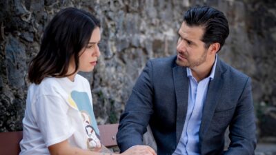 Joana (Camila Valero) e Gabriel (Brandon Peniche) conversam em banco diante de muro na novela A História de Joana, a Virgem