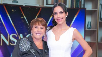 Márcia Fernandes e Daniela Albuquerque sorriem lado a lado no estúdio do Sensacional diante de painel do programa