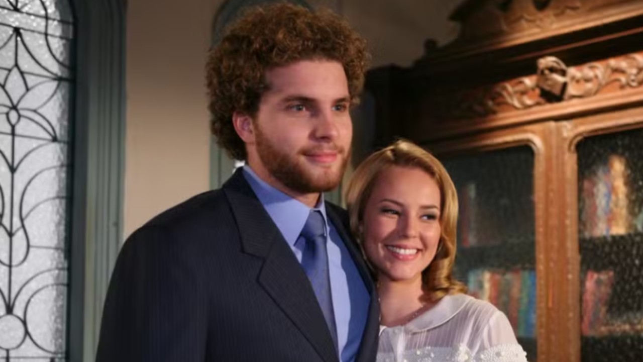 Marcos (Thiago Fragoso) de terno azul ao lado de Sônia (Paolla Oliveira) em cena da novela O Profeta