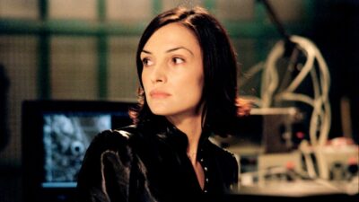 Rachel (Famke Janssen) de roupa preta olha para o lado em laboratório com monitores ao fundo em Sou Espião