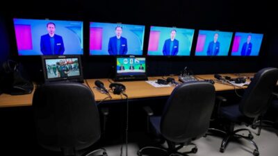Mesa de transmissão com monitores exibindo programação do SBT e equipamentos usados na cobertura da Copa do Mundo