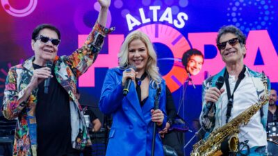 Bruno Fortunato, Paula Toller e George Israel cantam com microfones no palco do Altas Horas com banda ao fundo