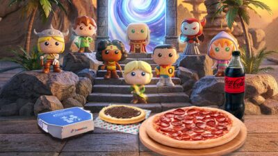 Bonecos colecionáveis da Caverna do Dragão diante de portal mágico com pizza de pepperoni, esfiha, refrigerante e caixa da Domino's