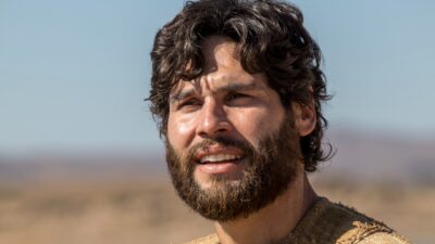 Dudu Azevedo como Jesus com barba e cabelos longos usando túnica bege em cenário aberto