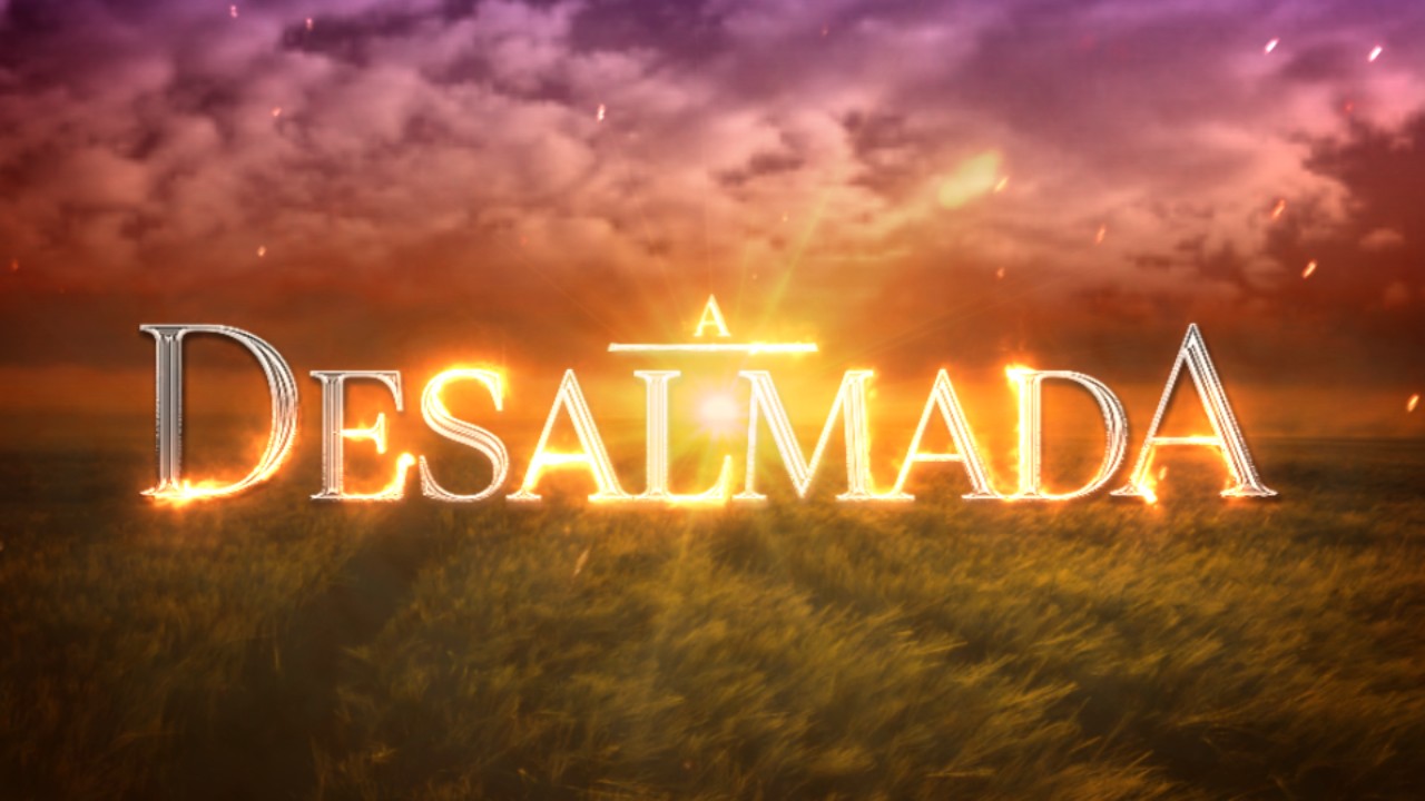 Logotipo da novela A Desalmada sobre campo de trigo ao pôr do sol com céu nublado em tons alaranjados e faíscas luminosas
